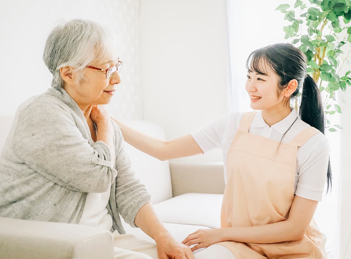 利用者様の肩に手を添えて笑顔で語り合う看護師