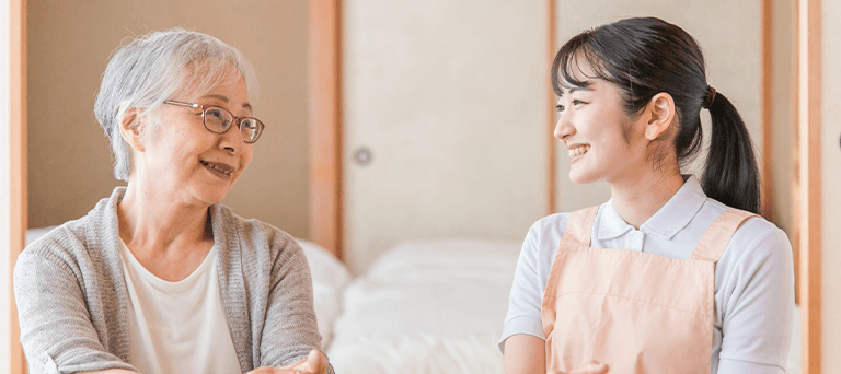 利用者様と笑顔で会話しながら体調を確認する看護師